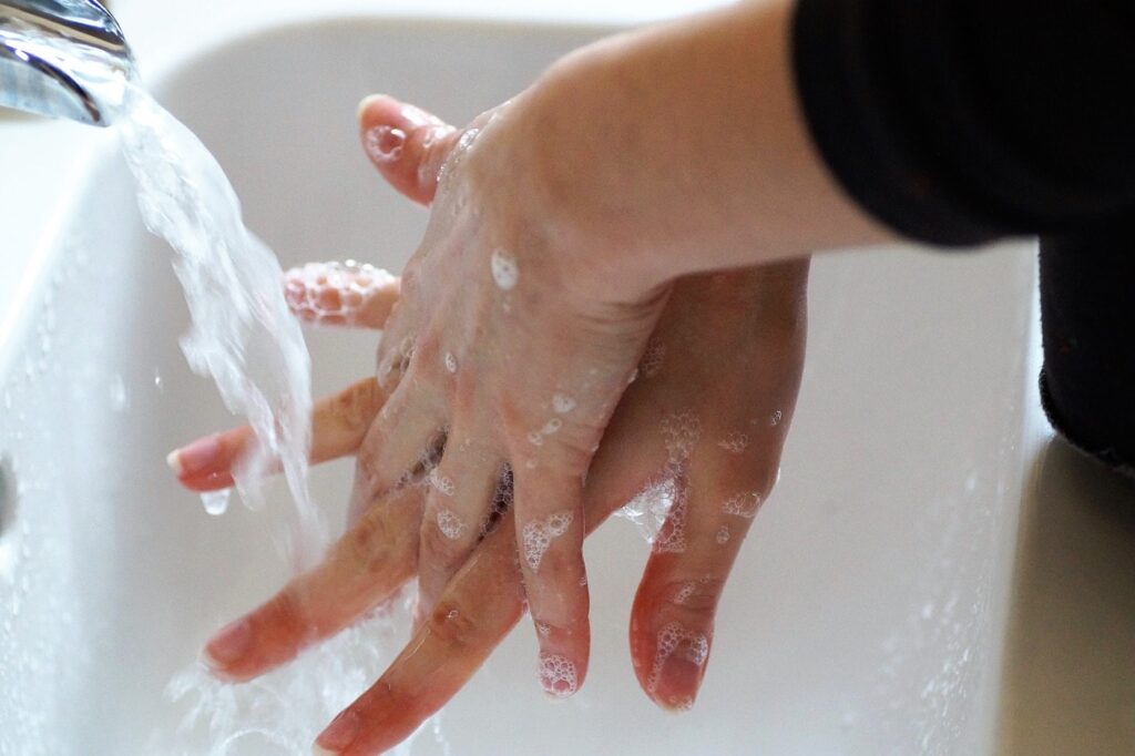 Person wäscht gründlich die Hände mit Seife unter fließendem Wasser.